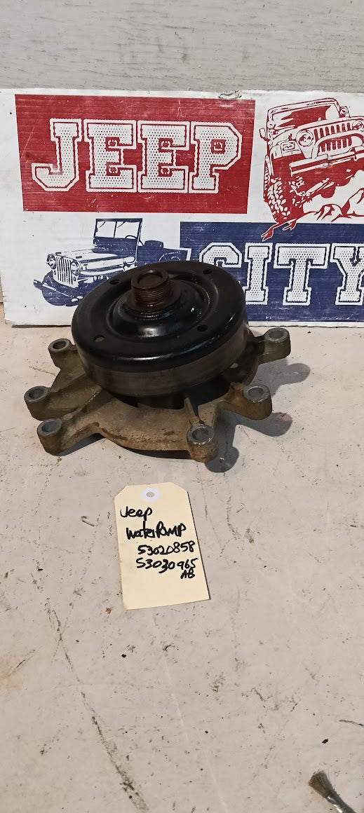 Water pump Jeep WJ 4.7L on a concrete surface with a Jeep City sign in the background