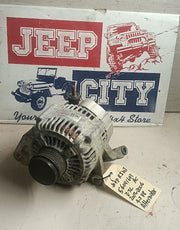A used automotive alternator with a handwritten price tag, displayed in front of a 'Jeep City' sign on a worn white surface.
