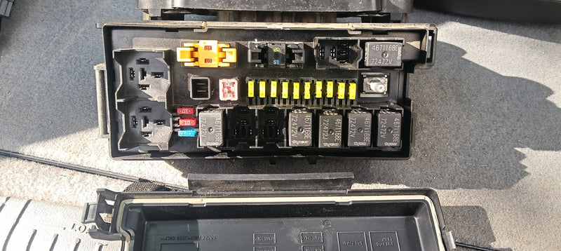 Car fuse box with various fuses on a gray surface