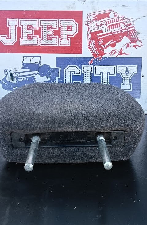 A used dark gray fabric-covered car headrest or seat backrest with two metal mounting posts, shown in front of a 'Jeep City' branded background.