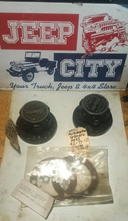 A set of black metal wheel hub covers and a plastic bag containing white gaskets, displayed on a white surface in front of a 'Jeep City' store sign.